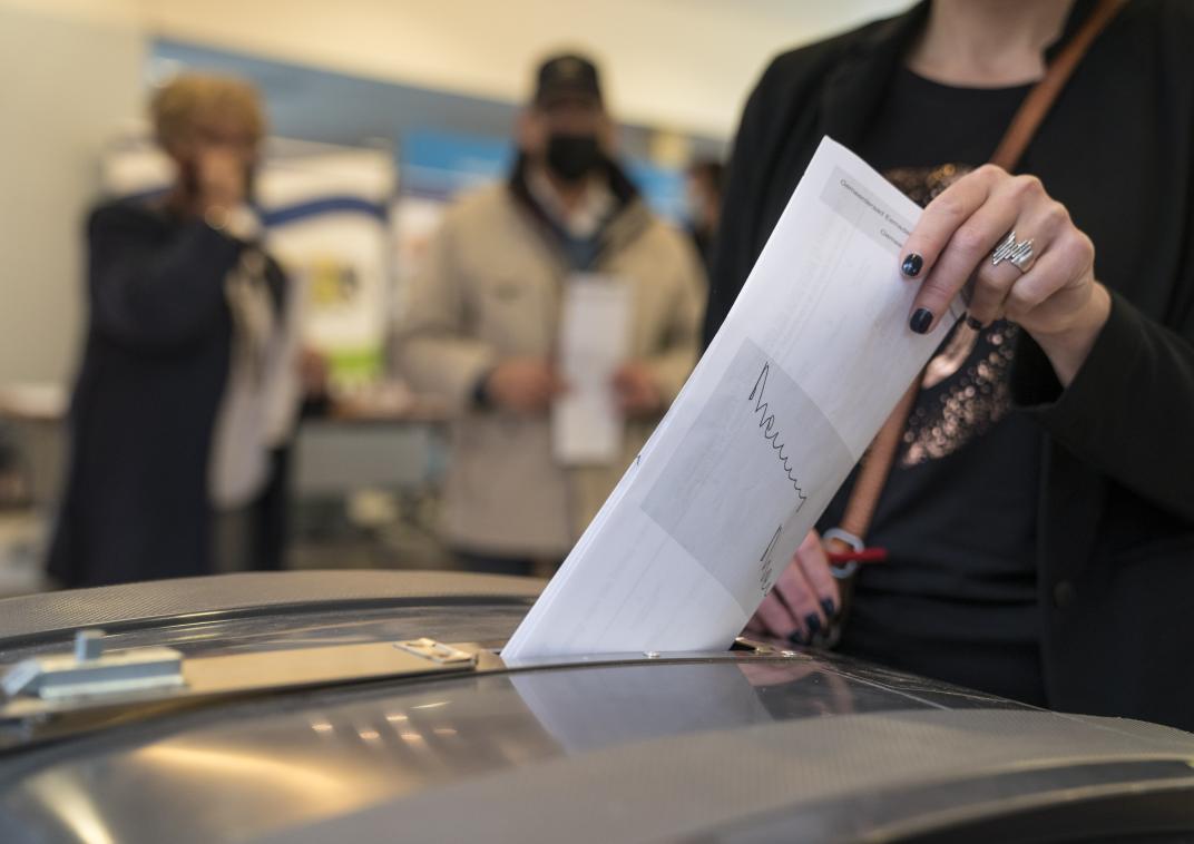 Een vrouw doet een stembiljet in een stembus
