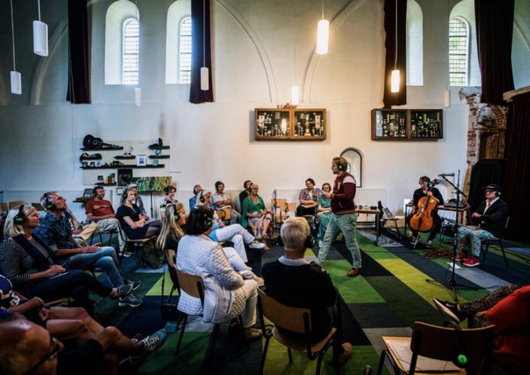 Een zaal vol mensen en 1 persoon presenteert iets