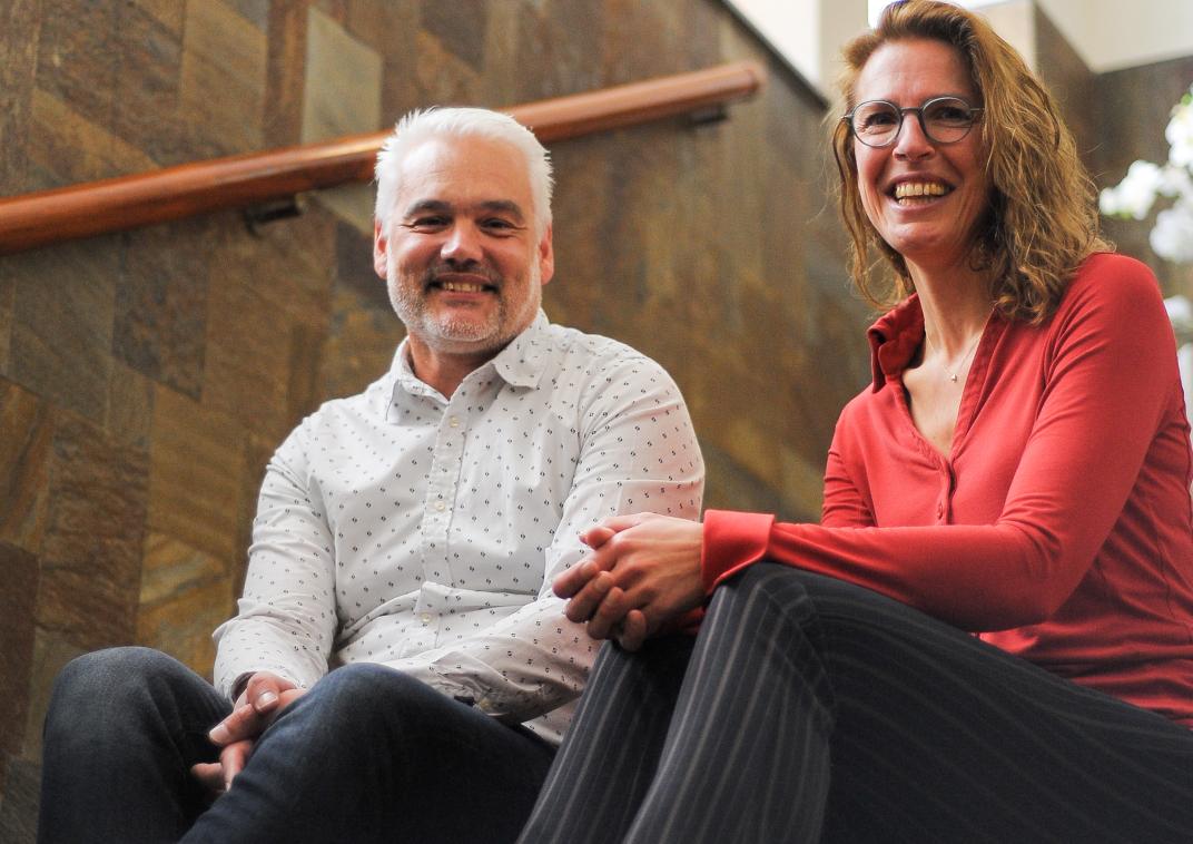 Twee medewerkers van gemeente eemsdelta zitten op een trap in het gemeentehuis in Delfzijl