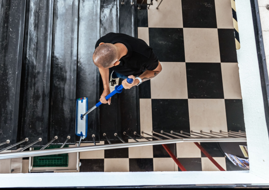 Een medewerker maakt de trappen in het gemeentehuis schoon