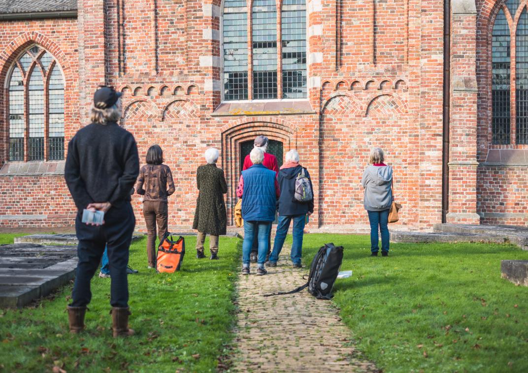 Deelnemers van de wandeling HECHT lopen de kerk in Loppersum in