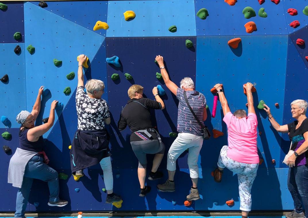 Vrouwen klimmen op een klimmuur