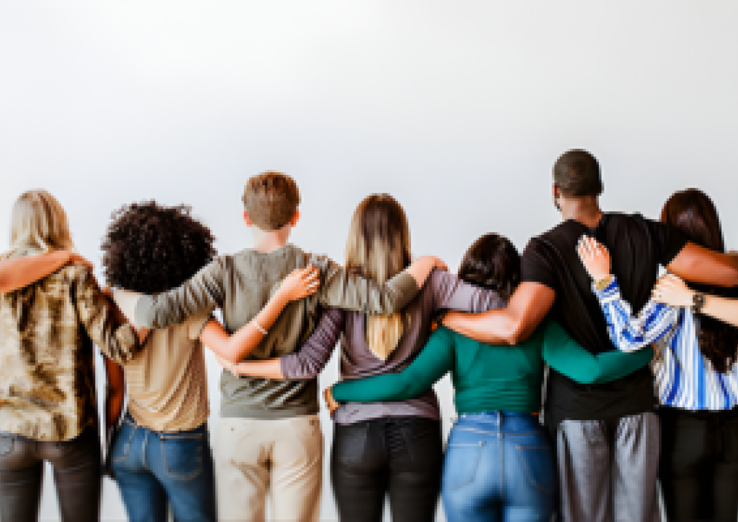 Personen staan met de arm om elkaar en vanaf de achterkant zie je deze personen. Samen weerspiegelen ze diversiteit.