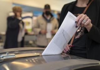 Een vrouw doet een stembiljet in een stembus