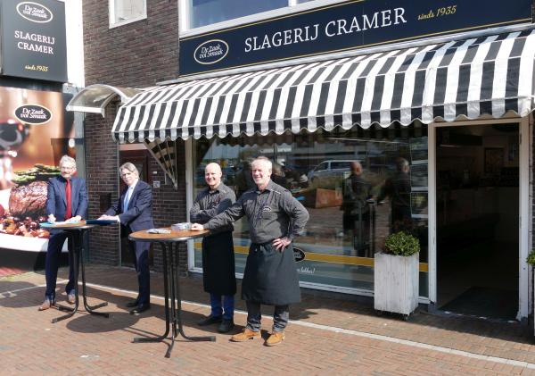 Burgemeester Gerard Beukema en Thomas en Ron Cramer van slagerij Cramer ondertekenen de overeenkomst voor de nieuwe slagerij