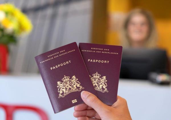 Een hand die twee Nederlandse paspoorten vasthoudt