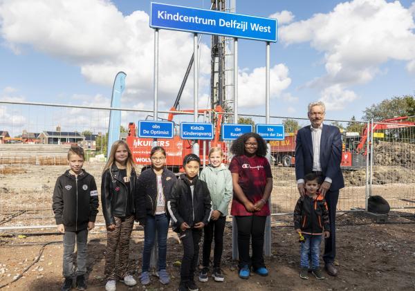 7 kinderen en wethouder Jan Menninga die samen voor de naamborden staan van de drie scholen en de kinderopvang die straks in het nieuwe kindcentrum Delfzijl West komen.