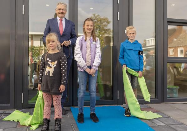 Wethouder Jan Menninga naast een drietal leerlingen van basisschool Het Baken in Delfzijl