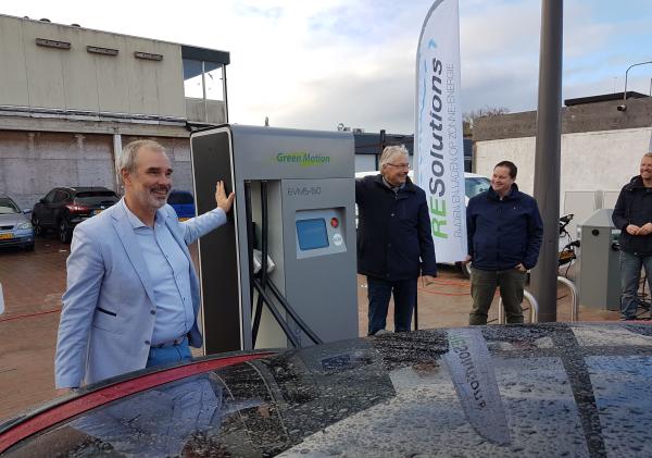 Wethouders Hans Ronde en Jan Menninga staan naast een laadpaal