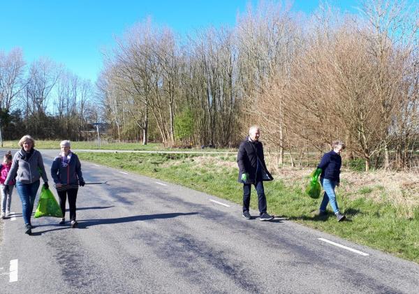 Vrijwilligers die zwerfaval opruimen langs de weg