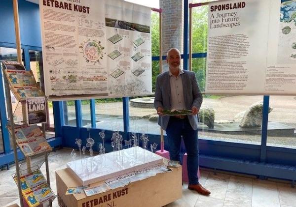 Wethouder Hans Ronde met eetbare producten uit de zee, zoals zeekraal en zeewier.