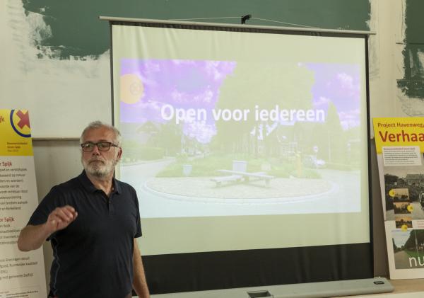 Man staat voor beamerscherm met daarop de tekst open voor iedereen