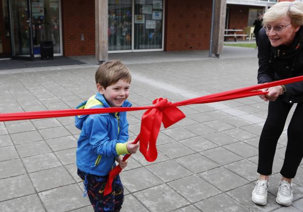 Leerling van kindschool 't Maar trekt glimlachend het rode lintje los om de school te openen.