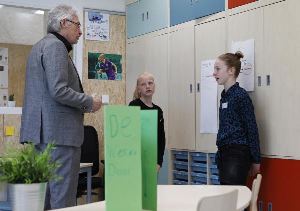 Wehouder Jan Menninga krijgt een rondleiding van 2 leerlingen.