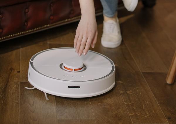 Een vrouw activeert een robot stofzuiger.
