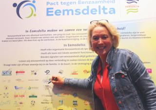 Wethouder Annalies Usmany-Dallinga tekent met een grote glimlach het Pact tegen Eenzaamheid Eemsdelta.