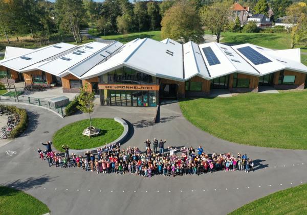 Luchtfoto van Kindcentrum de Kronkelaar en een groepje mensen.