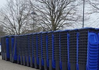 Rijen papiercontainers met blauwe deksels die zijn opgestapeld.