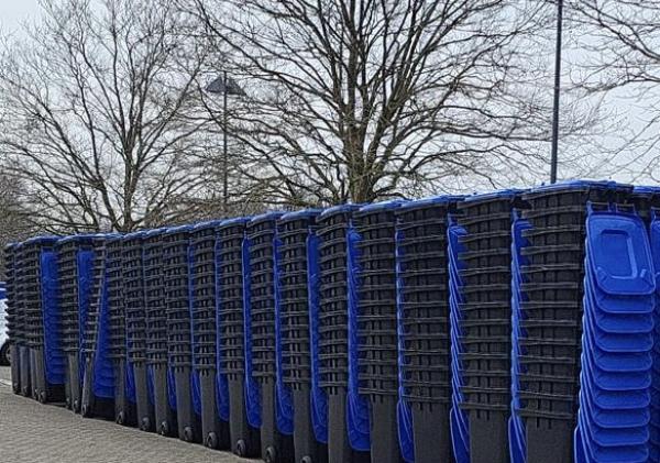 Rijen papiercontainers met blauwe deksels die zijn opgestapeld.