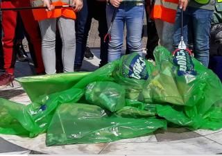 Een groepje mensen staat om groene zakken met zwerfafval.