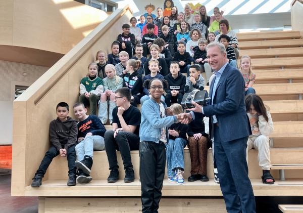 Groep kinderen op trap met wethouder ervoor.