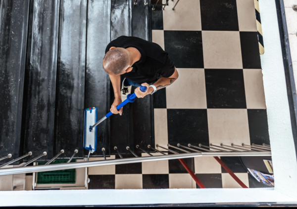 Een medewerker maakt de trappen in het gemeentehuis schoon