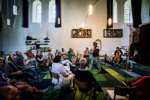 Een zaal vol mensen en 1 persoon presenteert iets