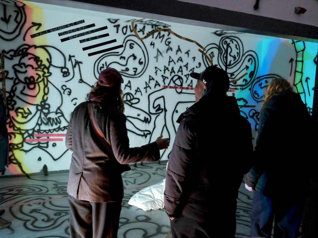 3 mensen staan voor een muur met graffiti