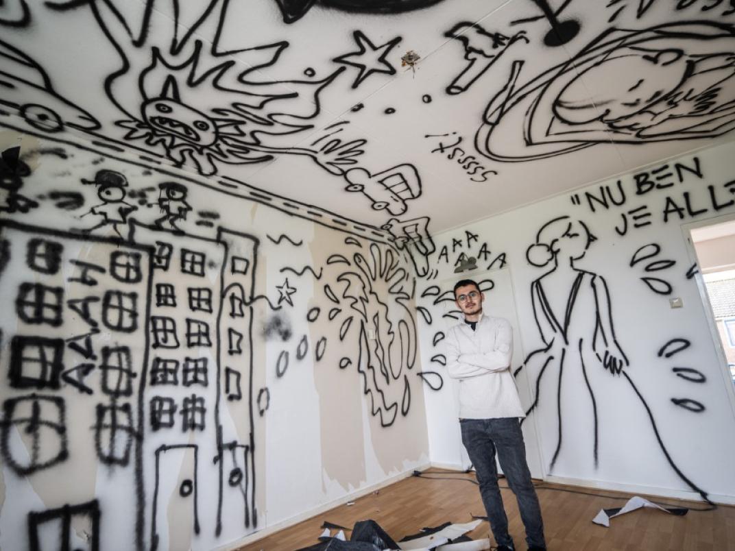 Persoon staat in kamer met allemaal graffiti