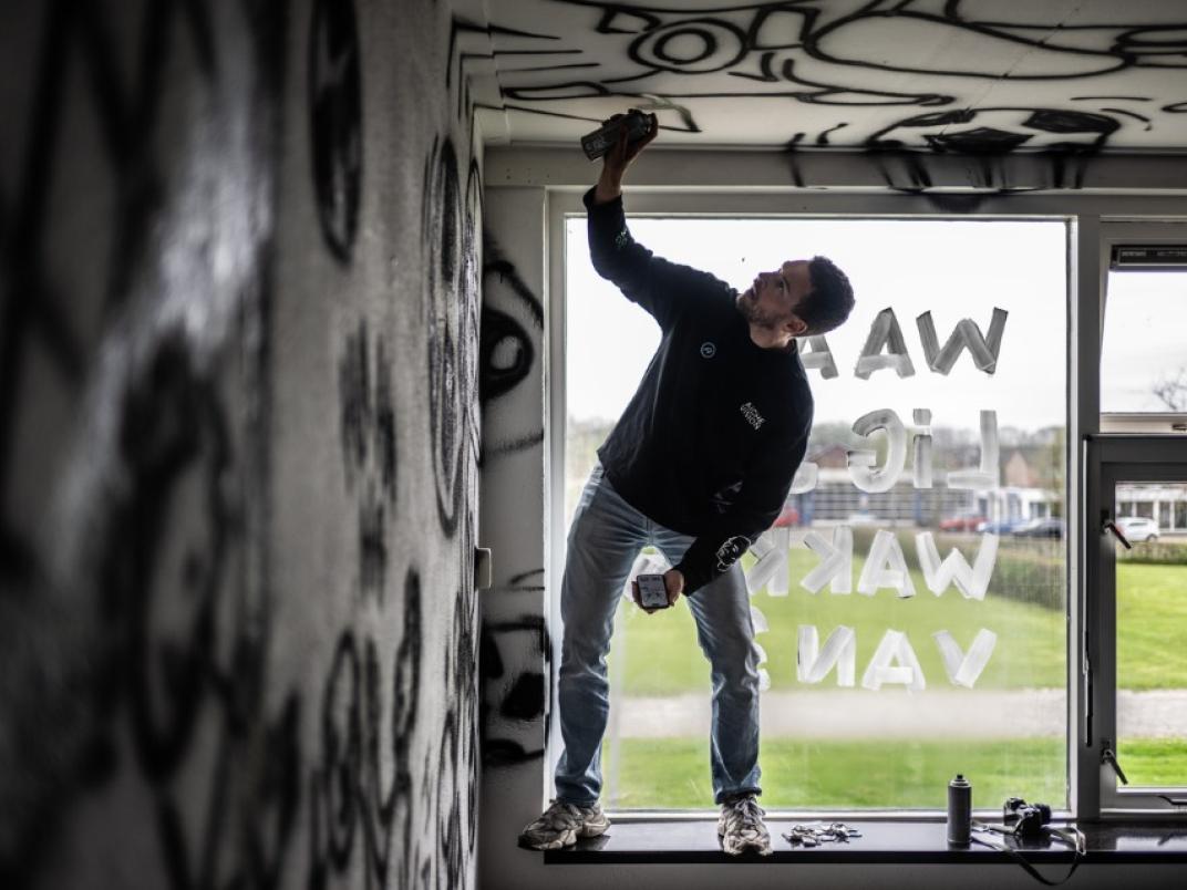 Persoon spuit graffiti in een gebouw
